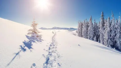 Verschneiter Berg mit Sonne am Horizont einer traumhaften Winterlandschaft-placeholder